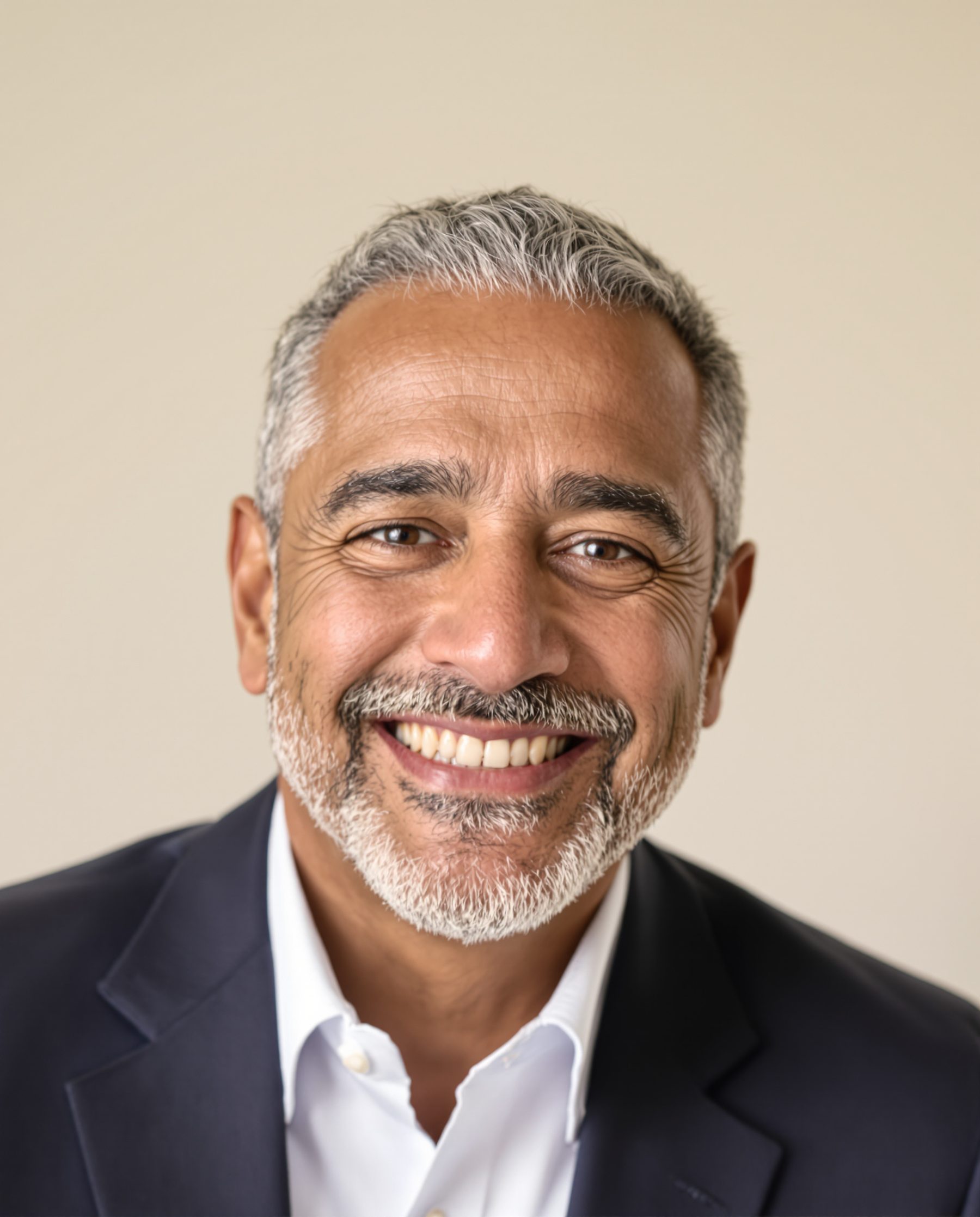 Hombre de unos cincuenta años con barba canosa sonriendo con dientes sanos.
