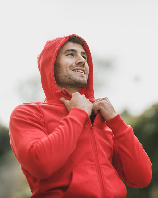 Coach de movilidad sonriendo al aire libre con sudadera roja