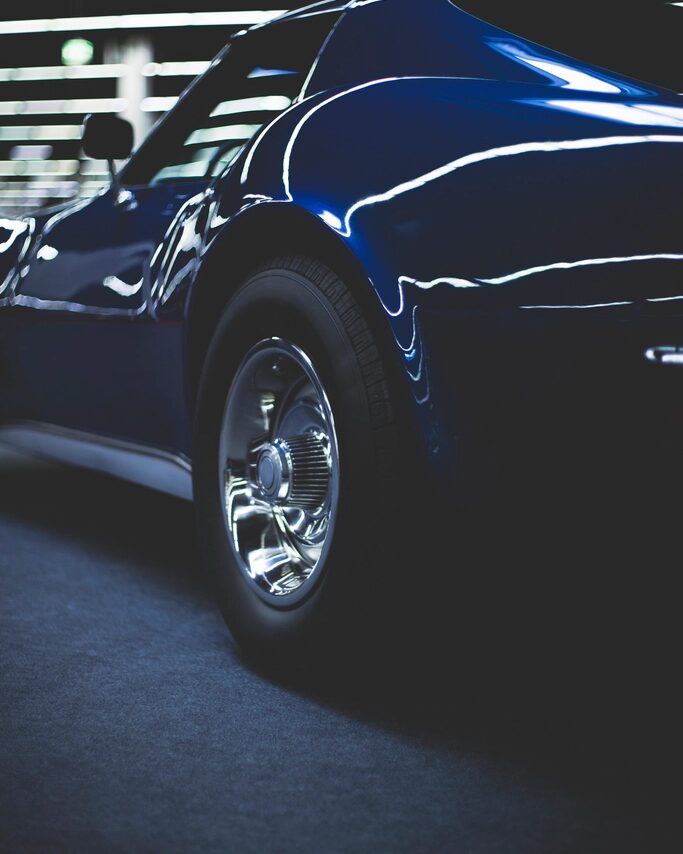 Carro azul oscuro con la pintura recién pulida reflejando las luces del garaje